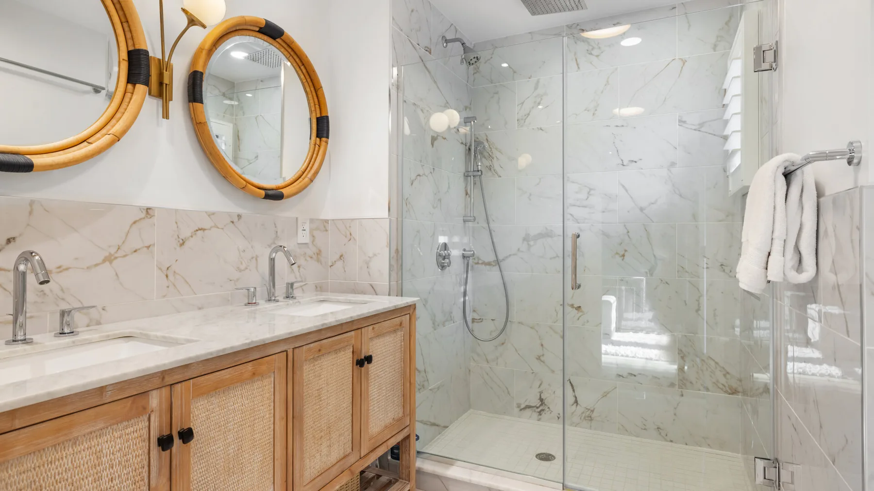 Un baño con un tocador doble y una ducha con mampara de vidrio.