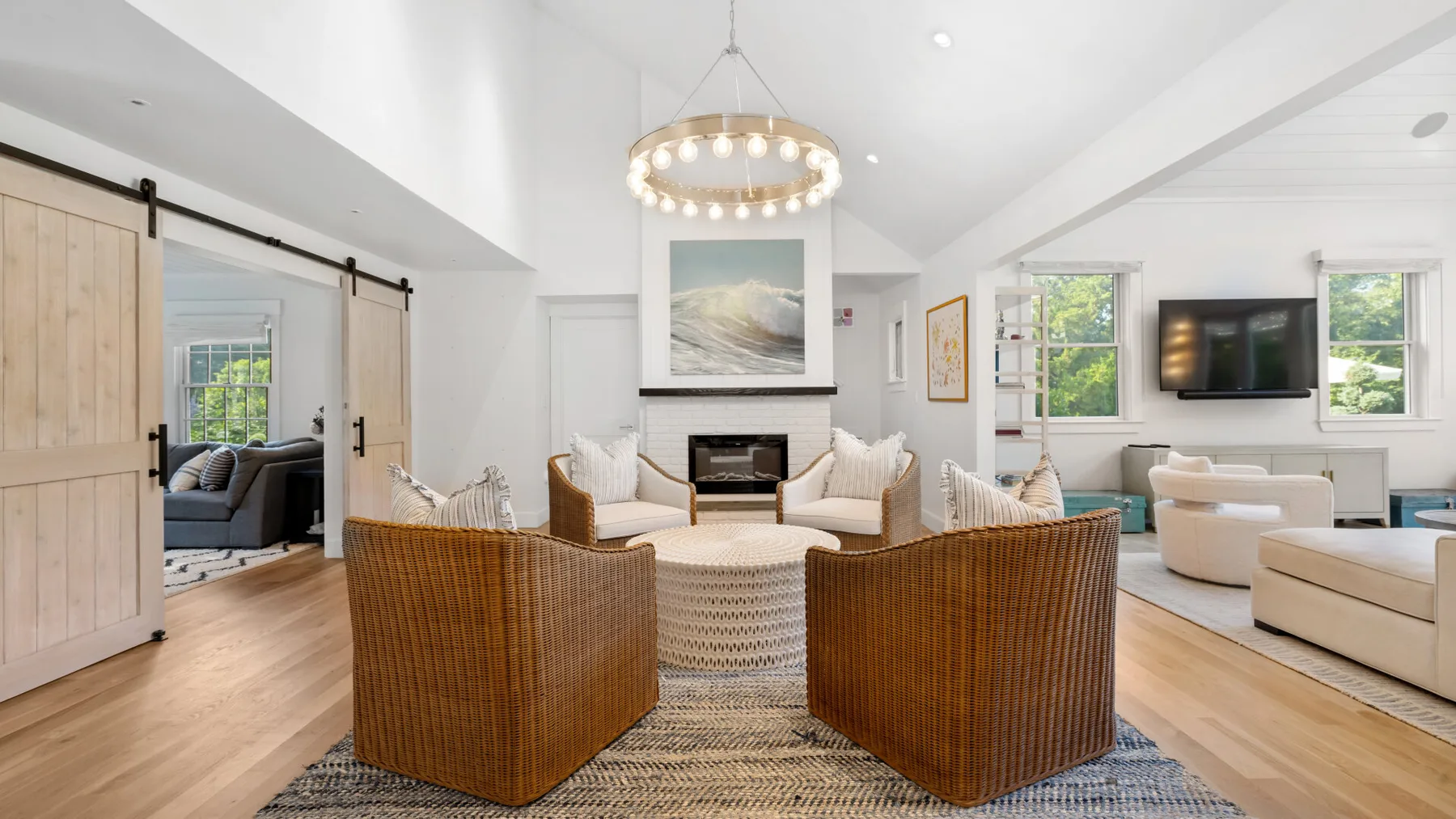 A bright living room with woven seating arranged around a fireplace.