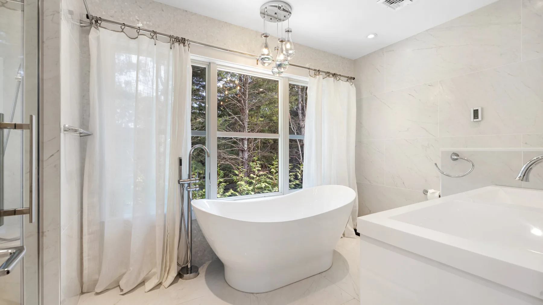 Un baño luminoso con una bañera exenta junto a una ventana grande.