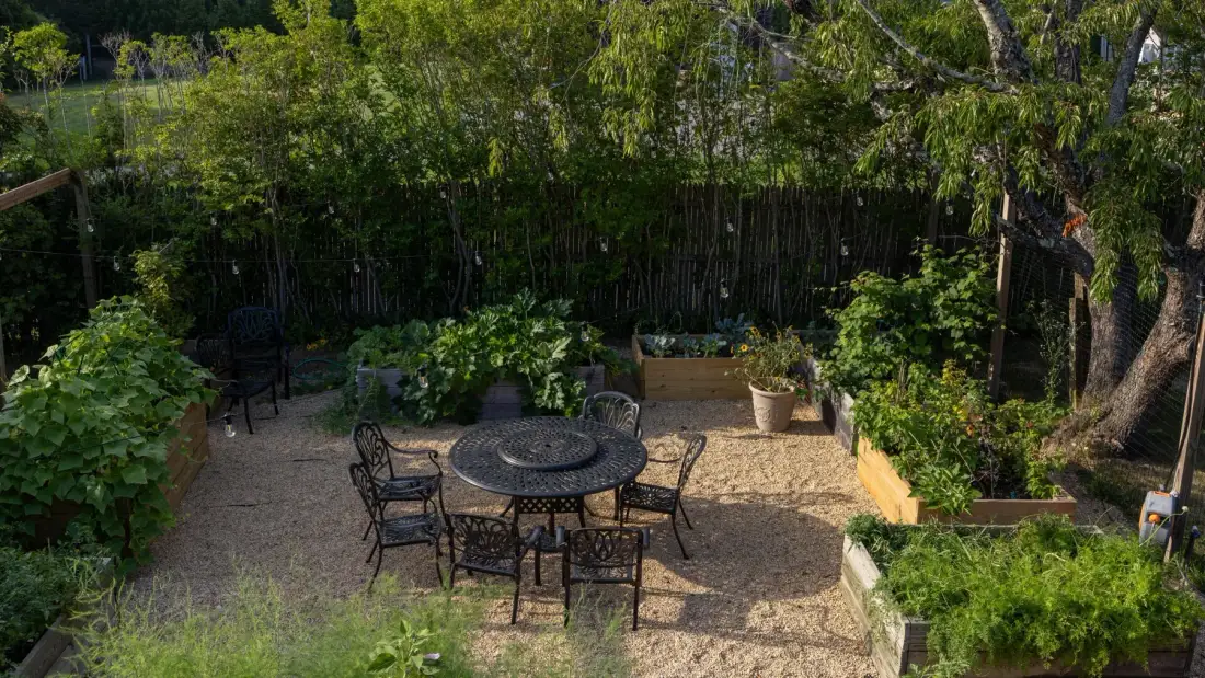 Zona de estar al aire libre con una mesa redonda y vegetación alrededor.