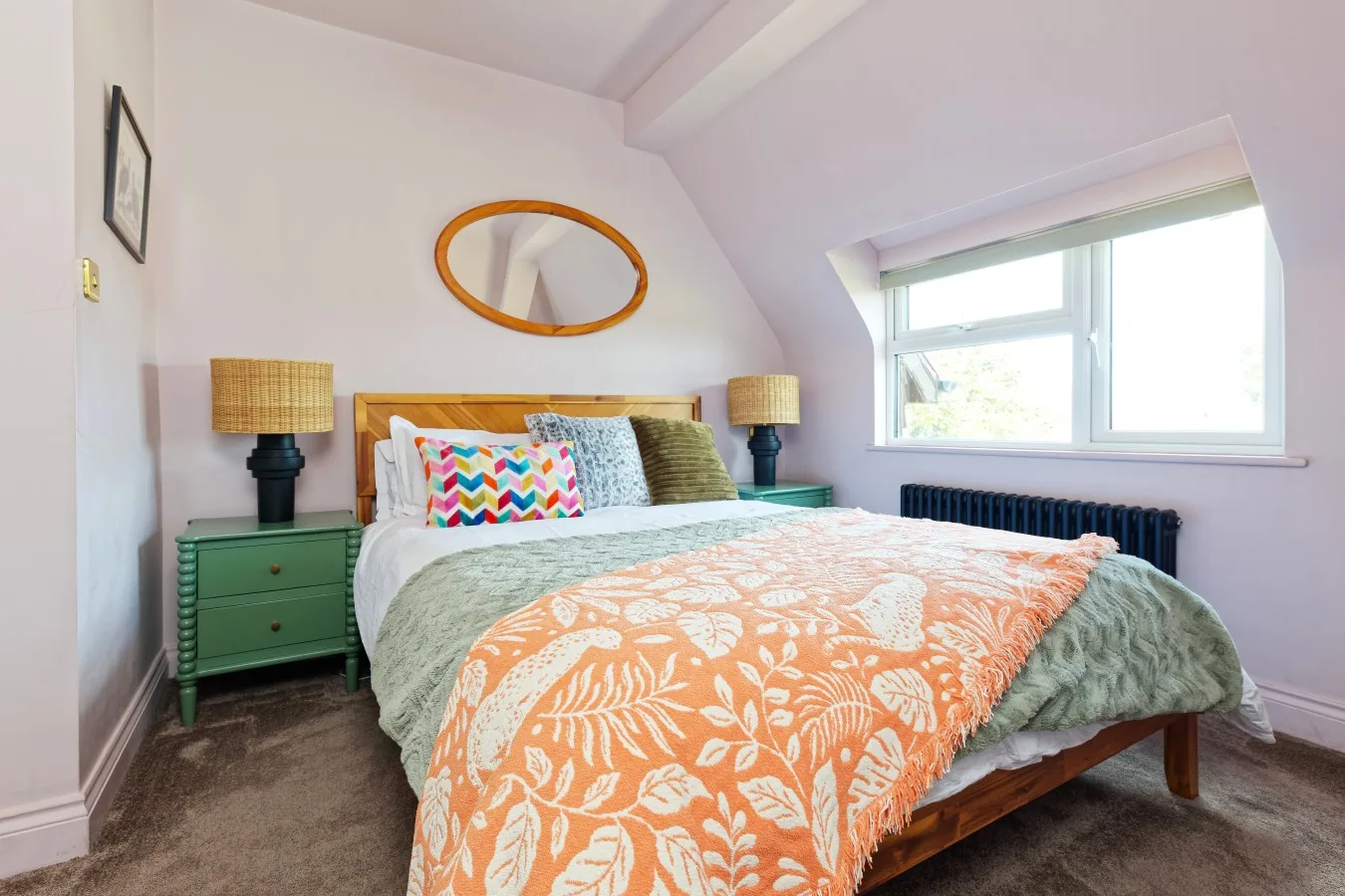 A bedroom with a bed dressed in patterned bedding and a window.