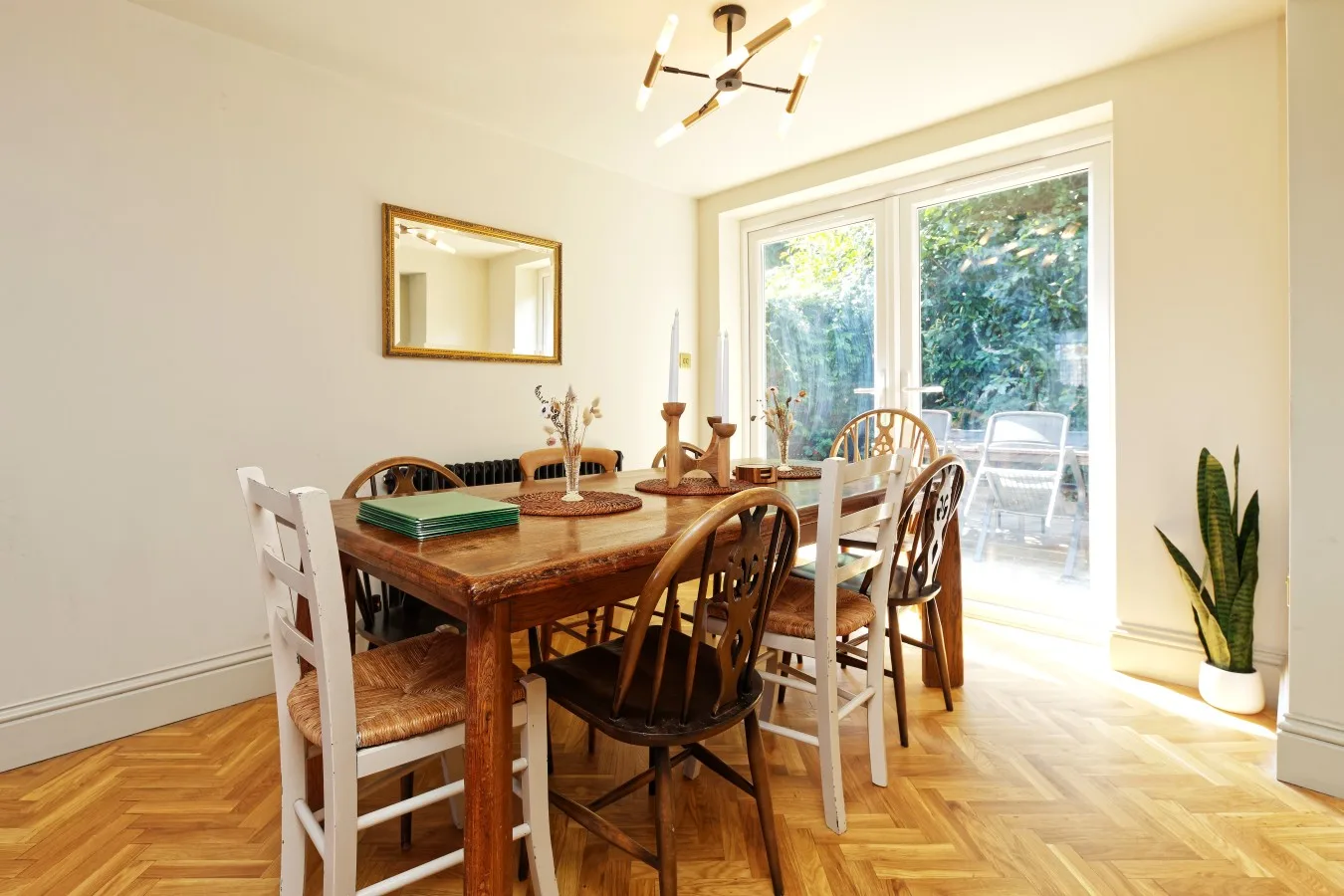 A dining area with a wooden table and chairs beside large glass doors.