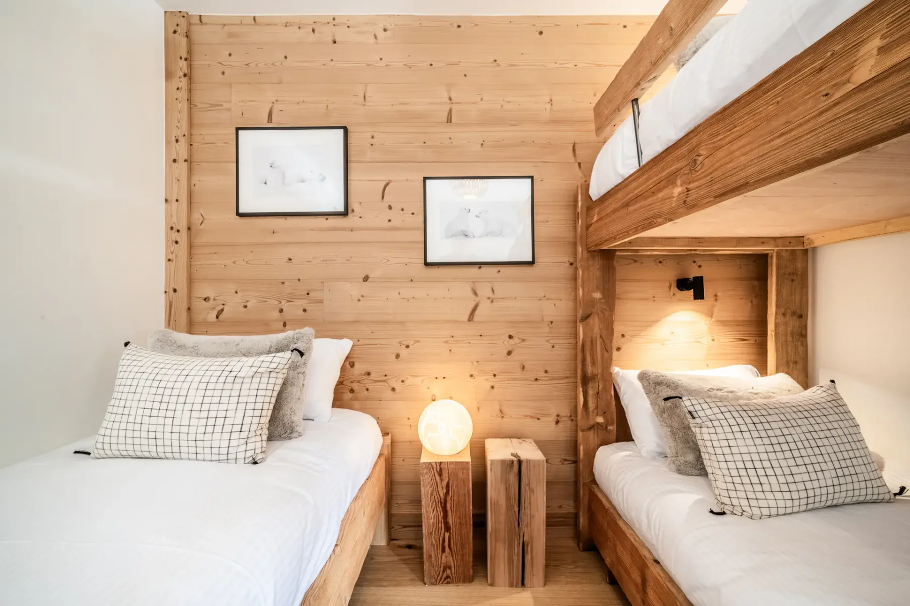 A wood-paneled bedroom with two beds and framed pictures on the wall.
