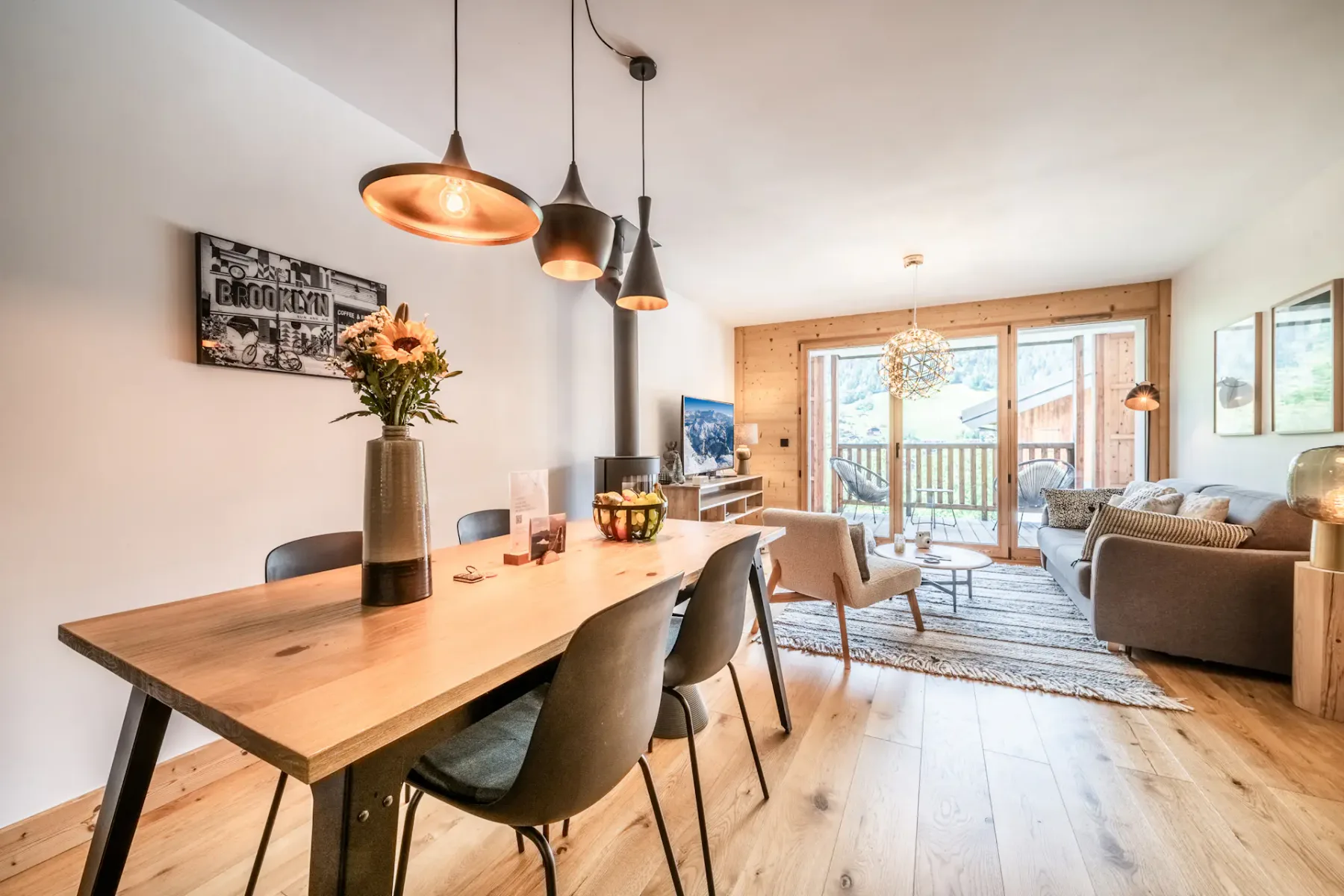 Modern kitchen with a wooden dining table, black chairs, a fireplace, and pendant lights.