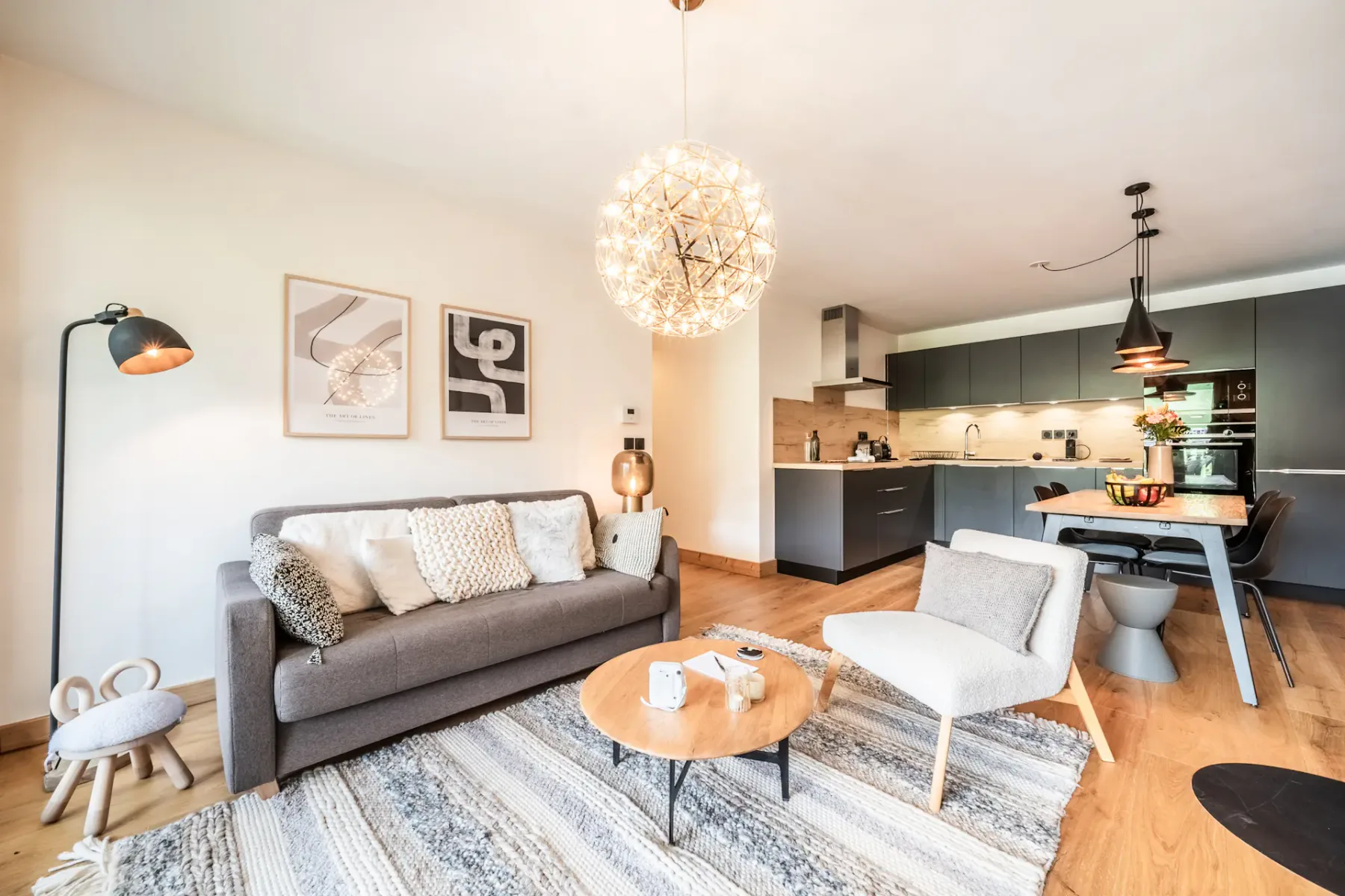 A living room with seating, a coffee table, and an open kitchen.