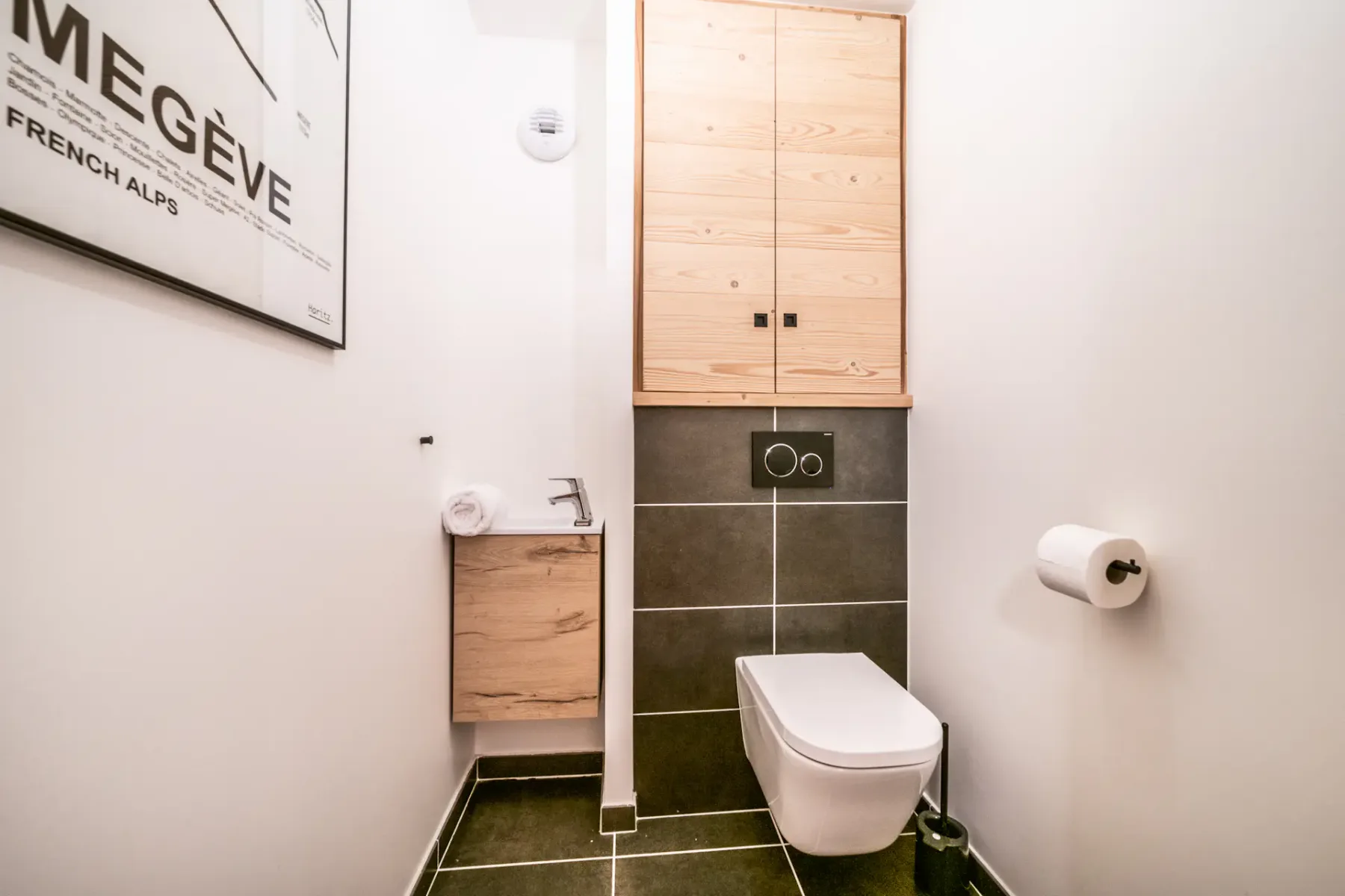 A modern bathroom with a wall-mounted toilet and wooden storage cabinets.
