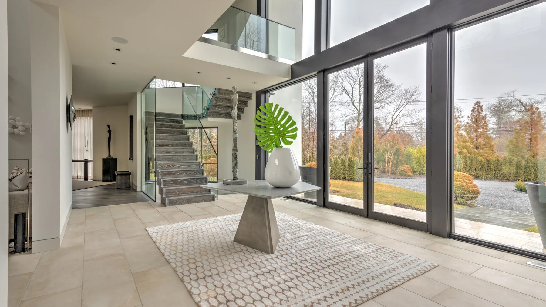 A bright modern interior opens onto floor-to-ceiling windows and a staircase.