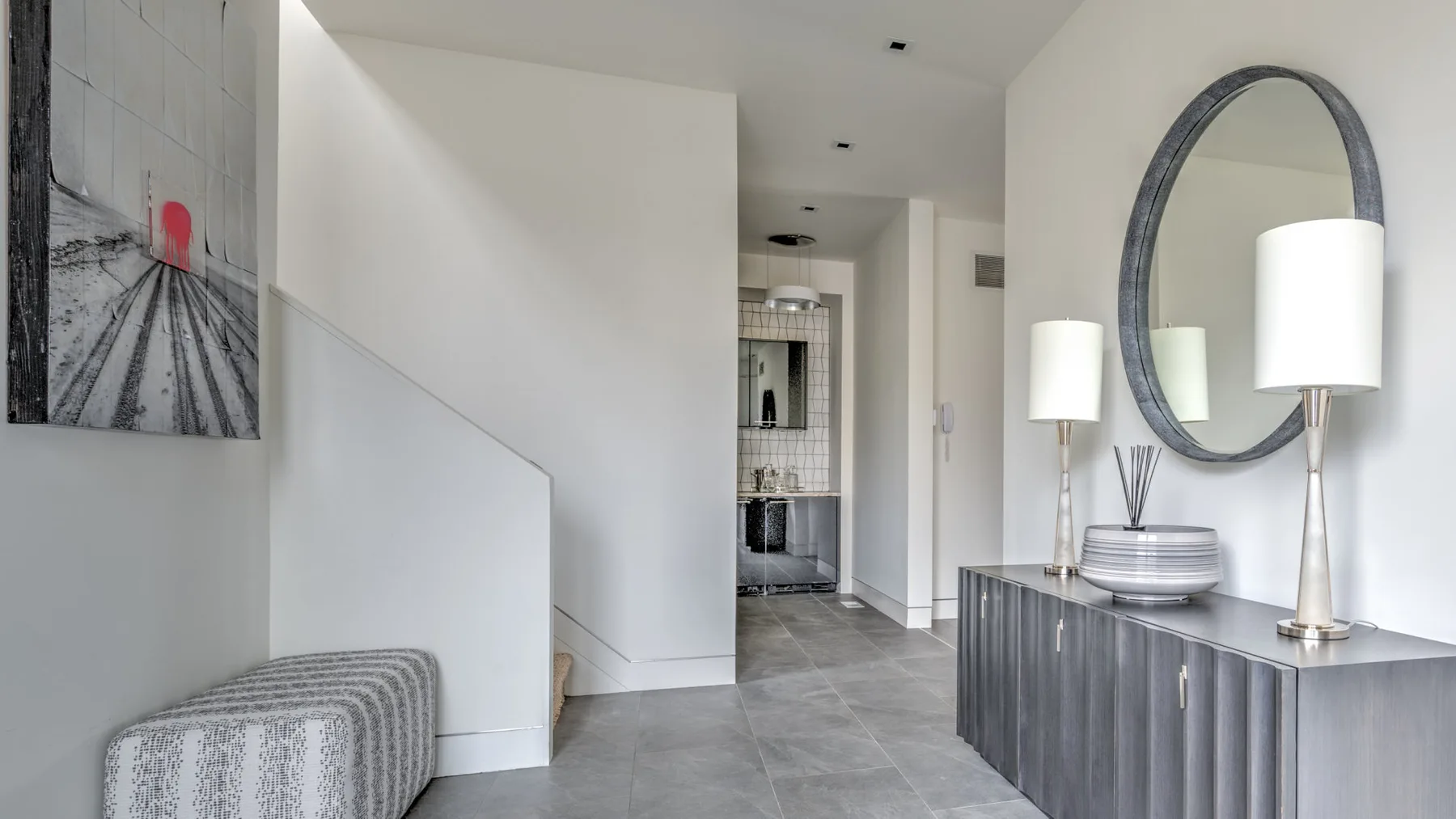 A bright hallway opens toward a tiled kitchenette, with a console and mirror nearby.