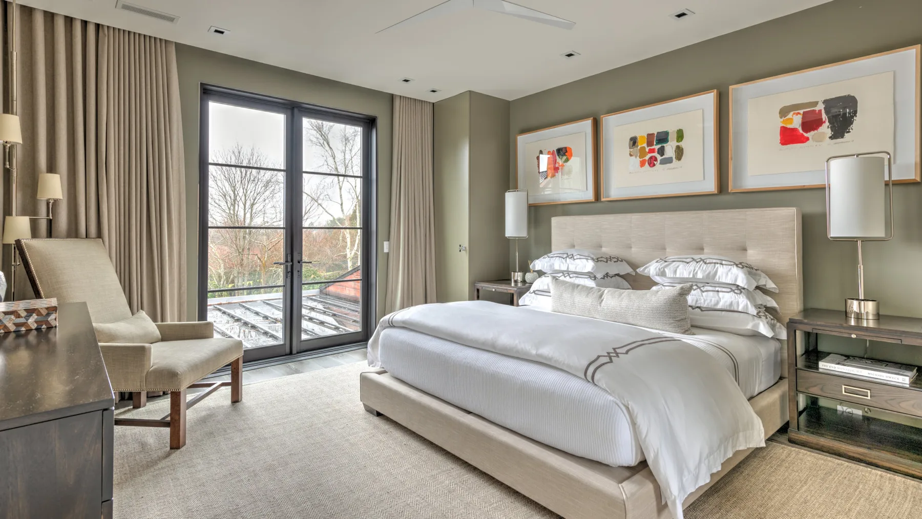 A bedroom with a large bed, bedside tables, and glass doors opening to a balcony.