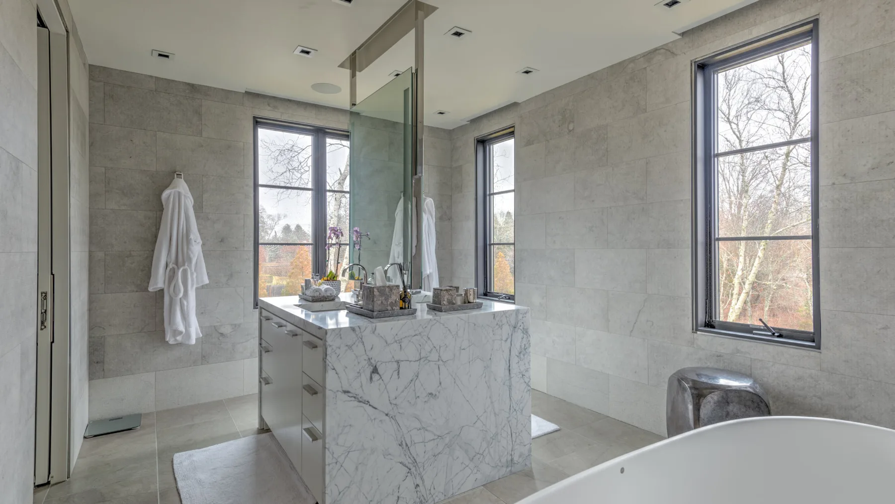 A bright bathroom with a marble vanity and a freestanding bathtub.