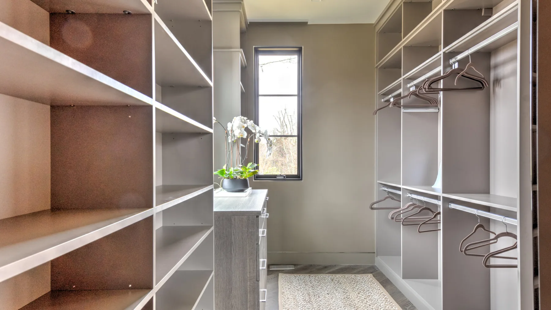 A walk-in closet with open shelving and hanging rails beside a window.
