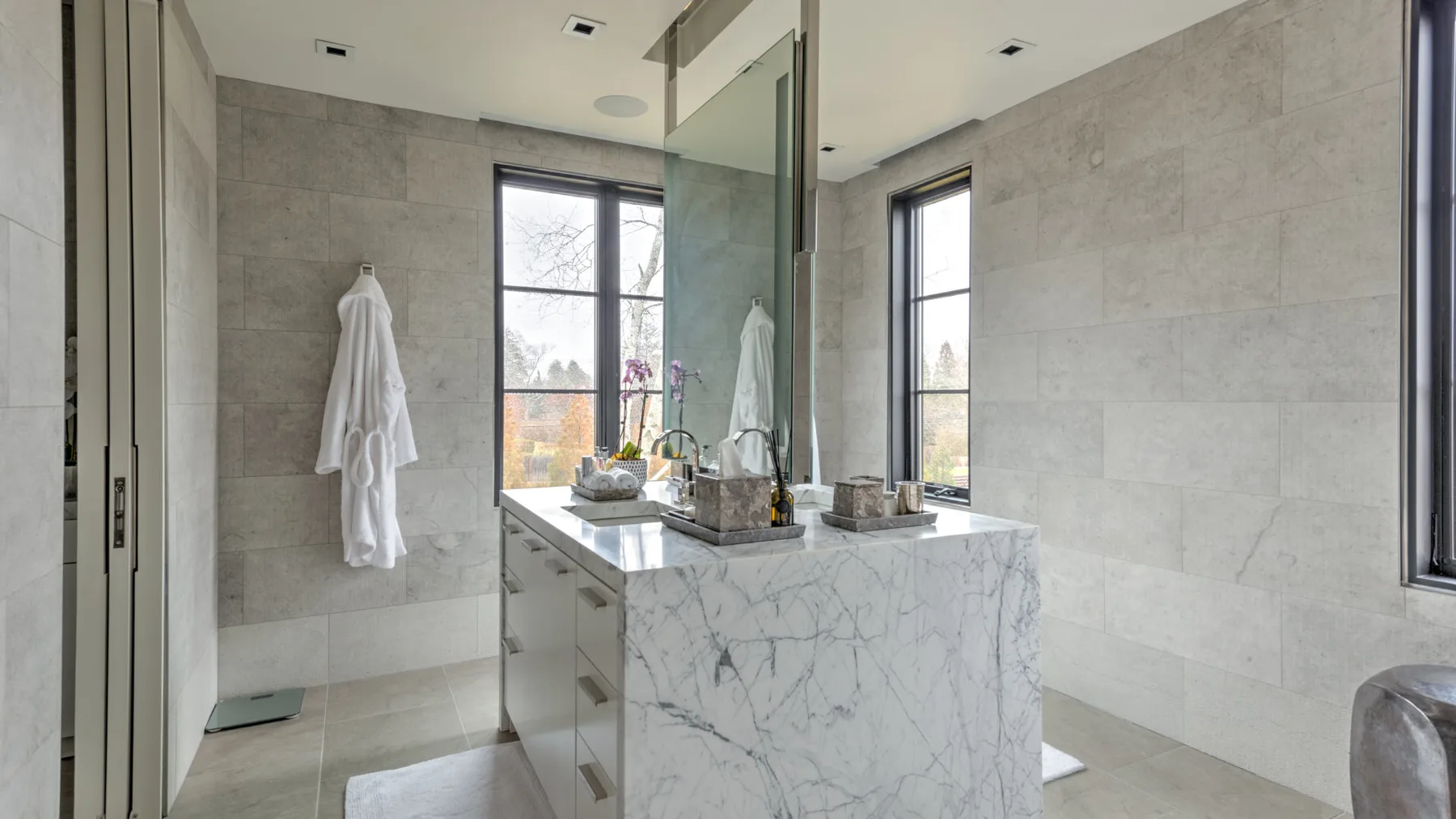 A tiled bathroom with a glass shower and a marble vanity.