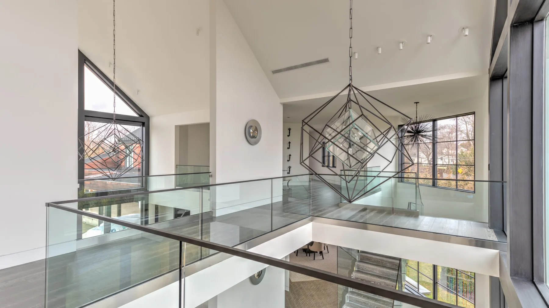 A bright modern interior with glass railings around an open upper-level walkway.