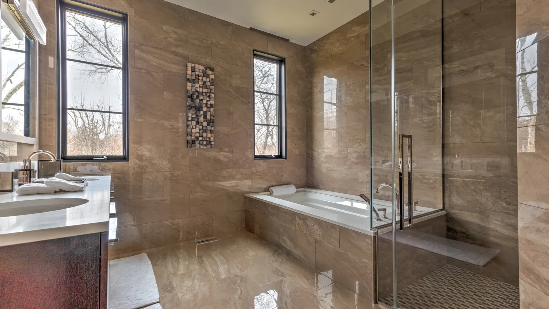 A tiled bathroom with a bathtub, glass shower, and sink.