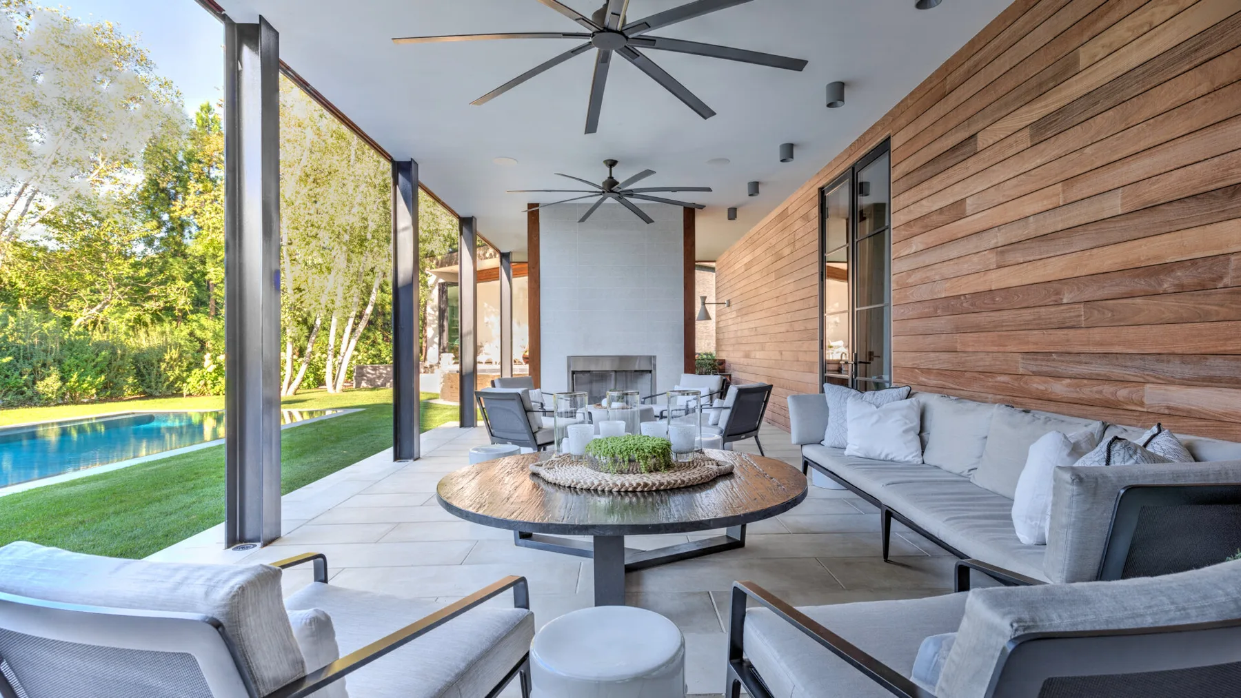 A covered outdoor lounge with cushioned seating and a view of the pool.