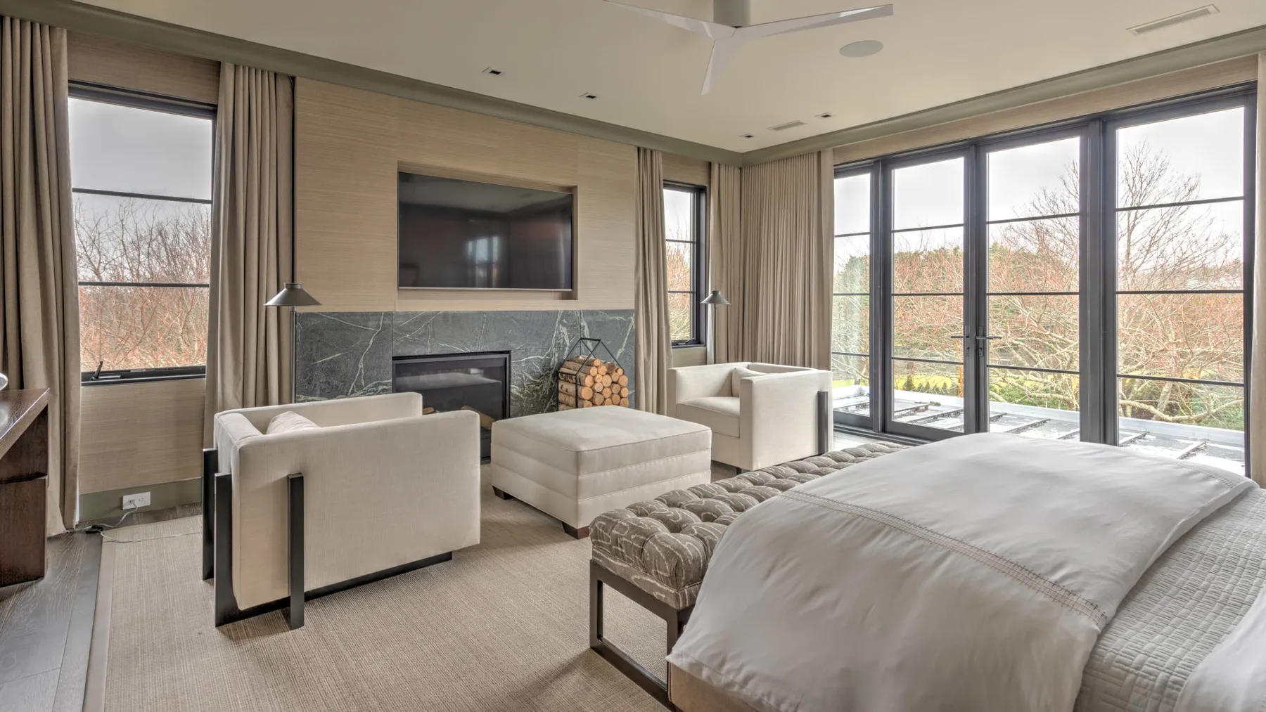 A bedroom and sitting area with a bed, seating, and large windows.