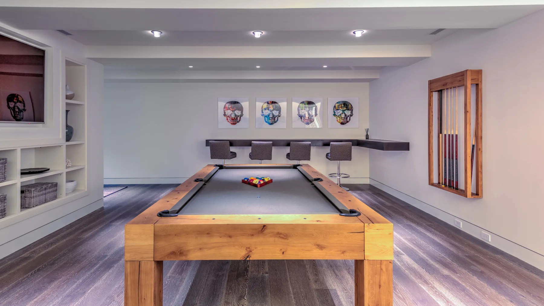 A game room with a pool table beneath framed wall art.