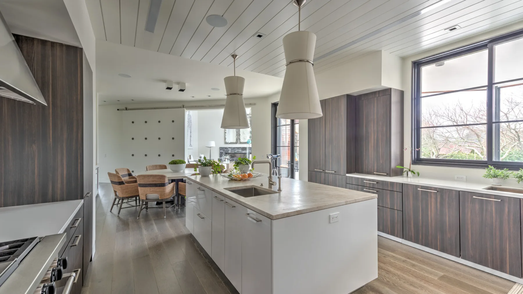 A bright kitchen with a central island, dining table, and large windows.