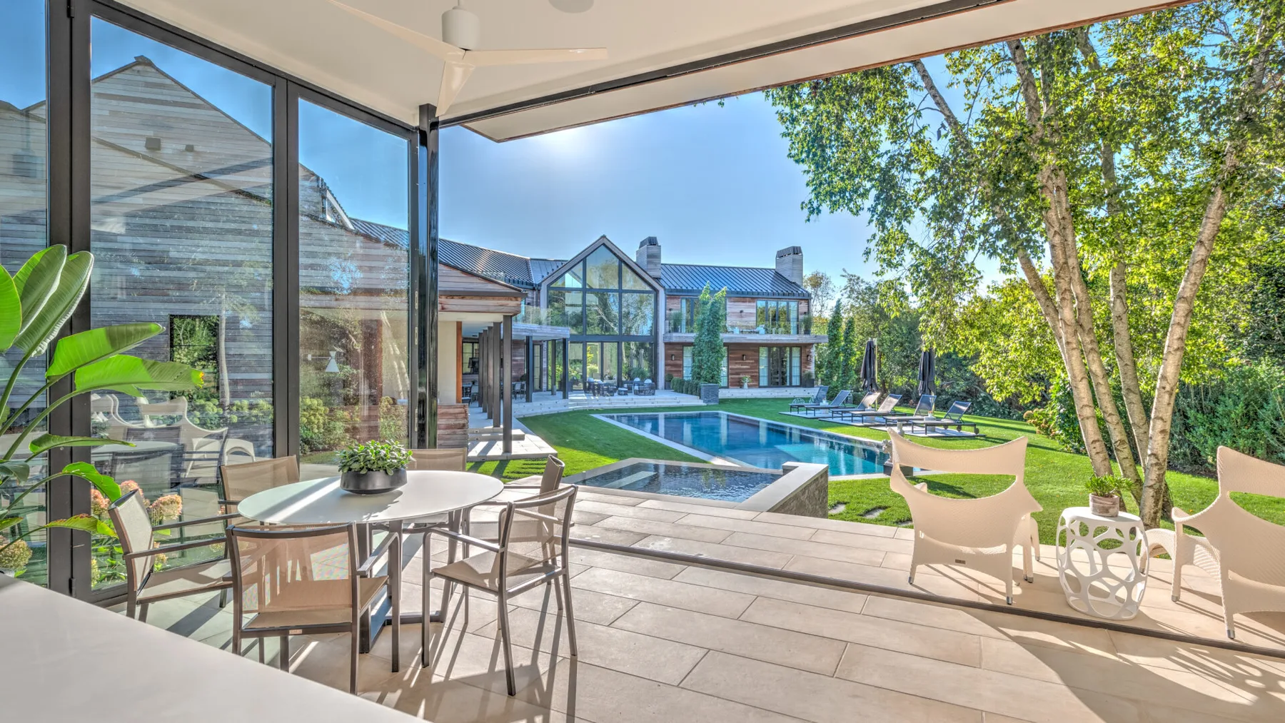 A covered outdoor patio overlooks a swimming pool and landscaped yard.