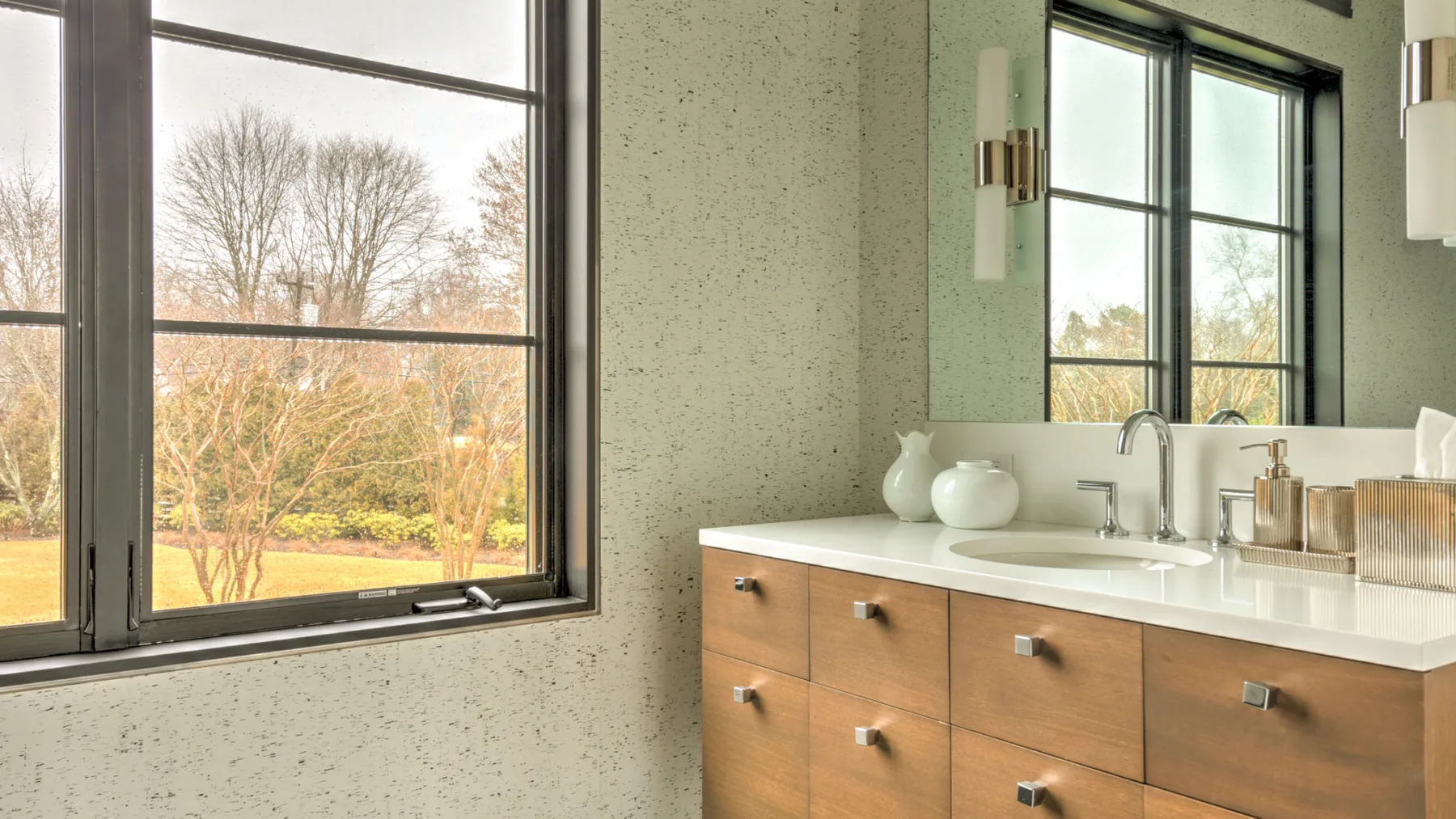 A bathroom vanity with a sink sits beside a large window.
