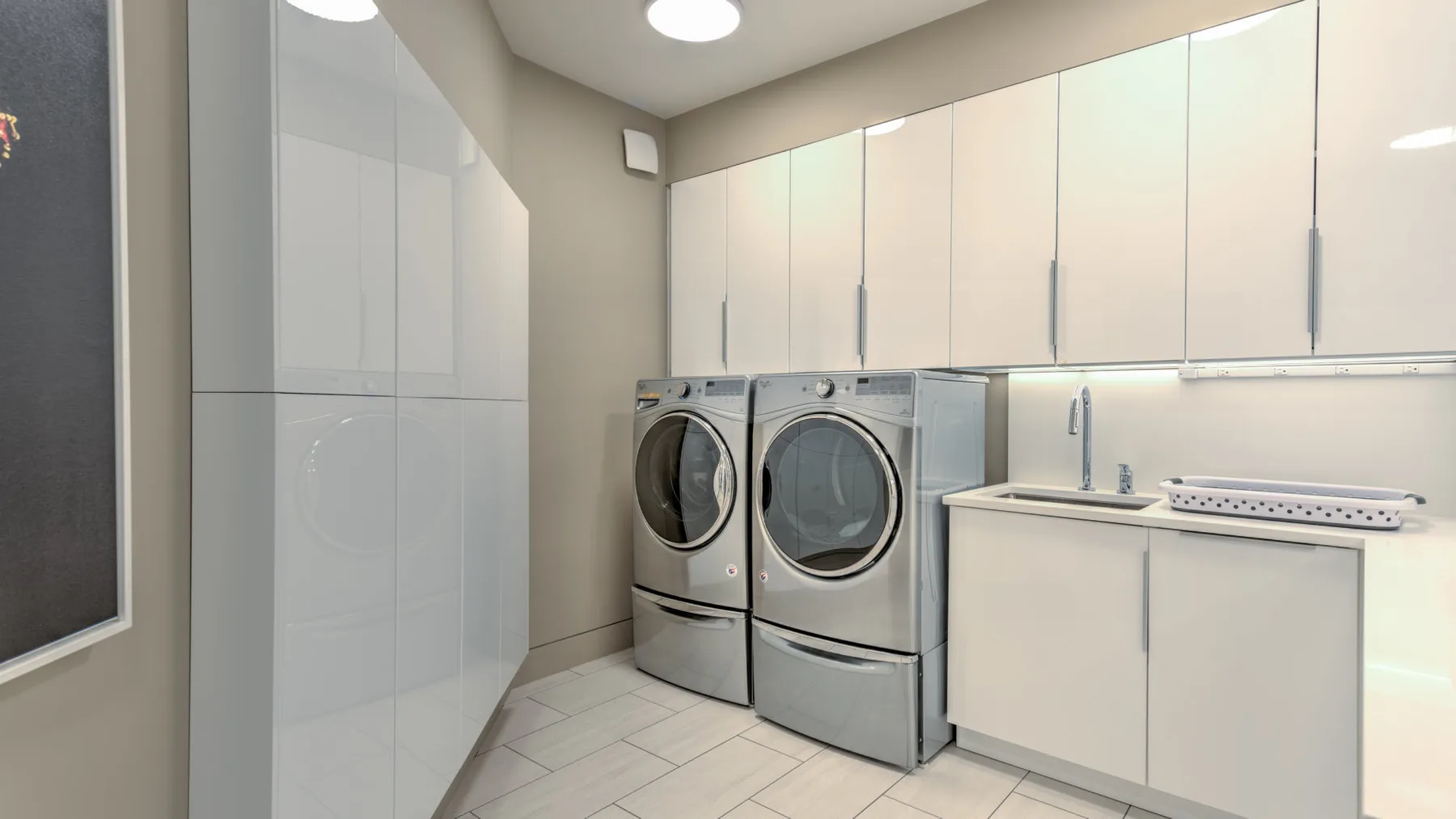 A laundry room with front-loading machines and white cabinets.