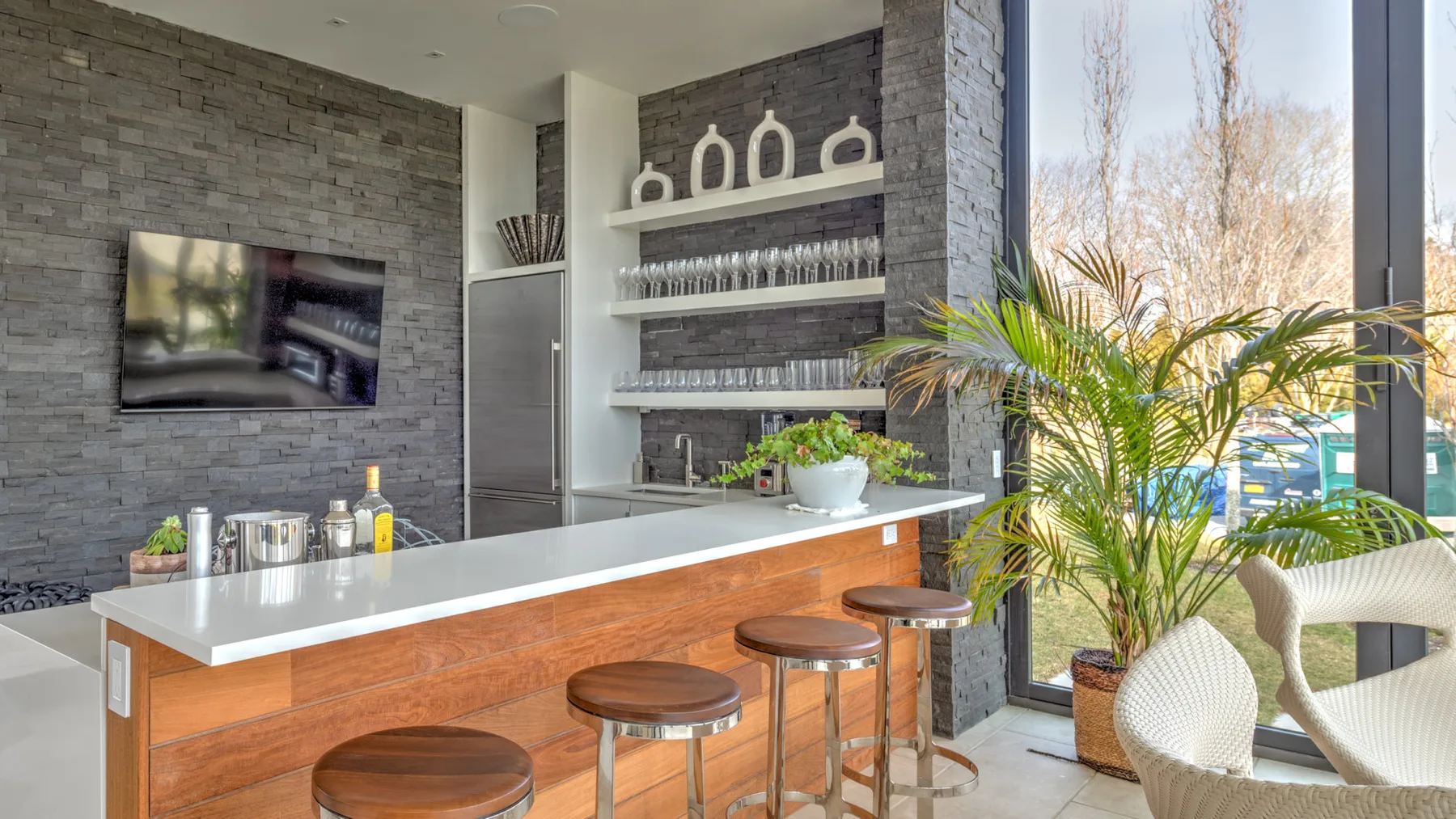 A bright lounge area with a long counter, stools, and large windows.