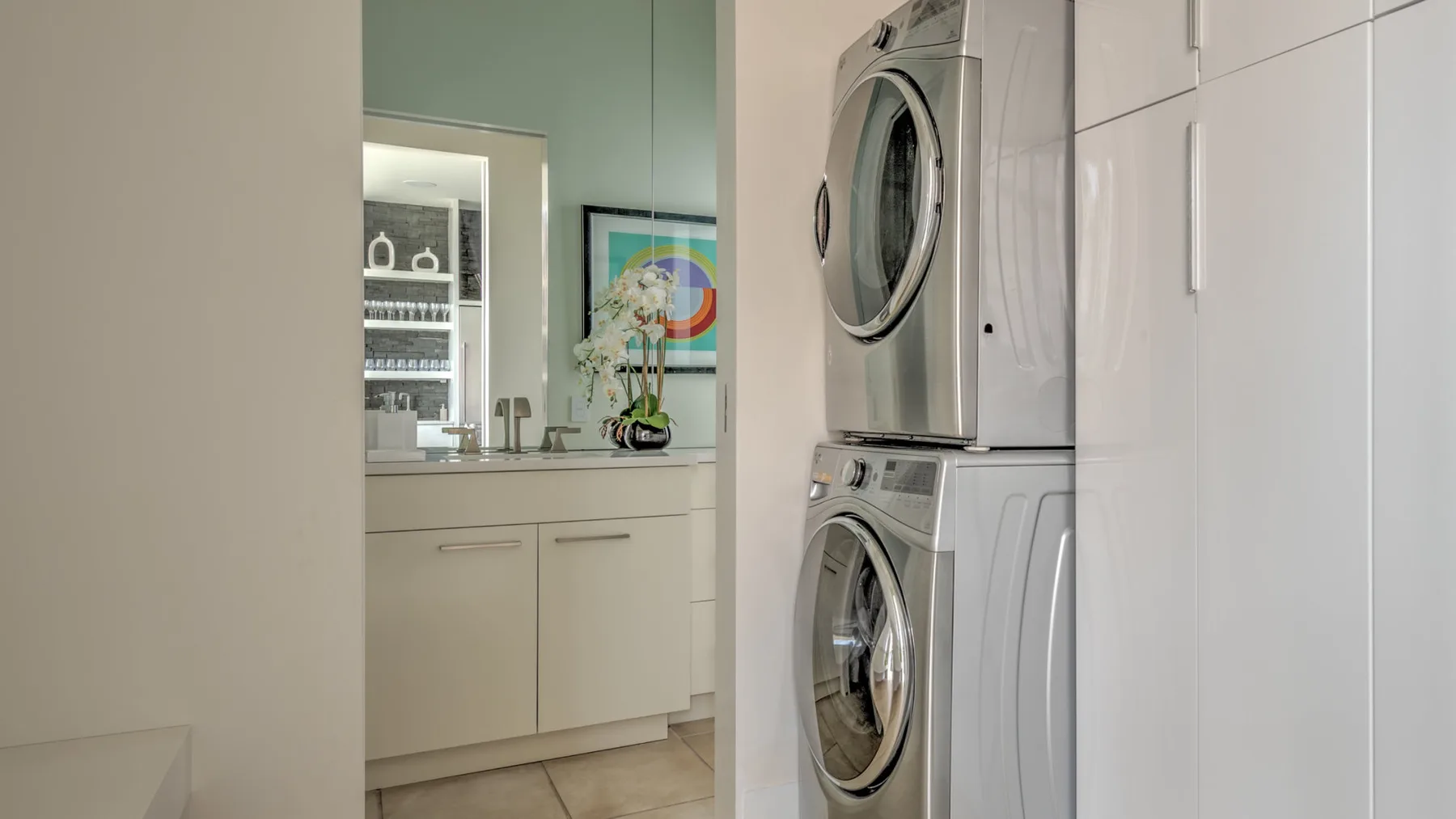 A laundry area with a stacked washer and dryer beside a bathroom vanity.