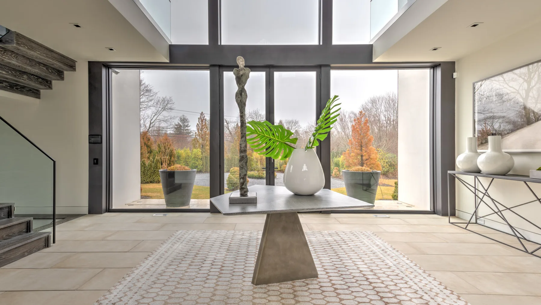 A bright living room with floor-to-ceiling windows and a sculptural table centerpiece.