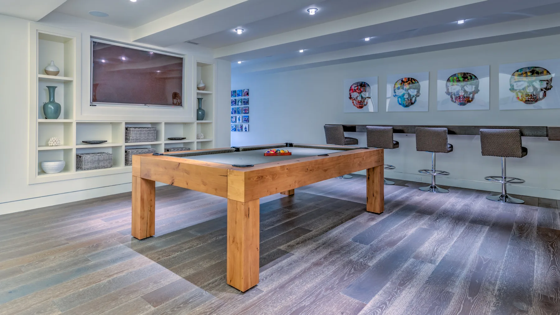 A game room with a wooden pool table and wall-mounted artwork.