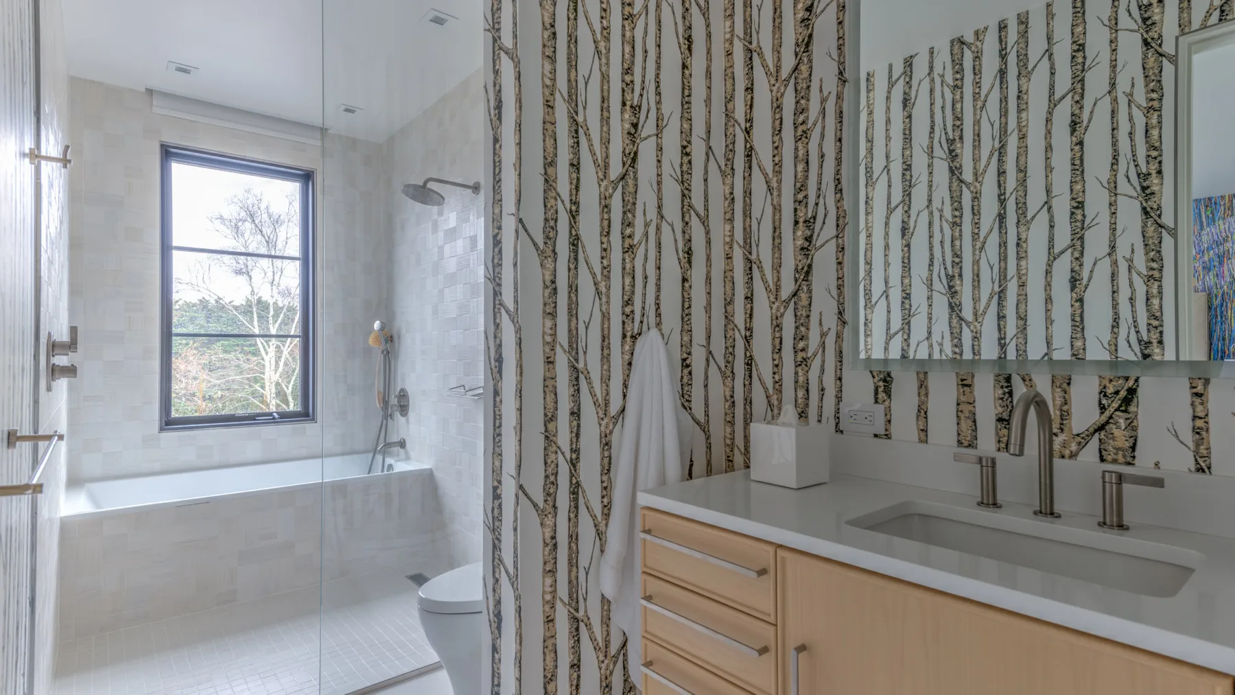 A bathroom with a bathtub beneath a window and a vanity.