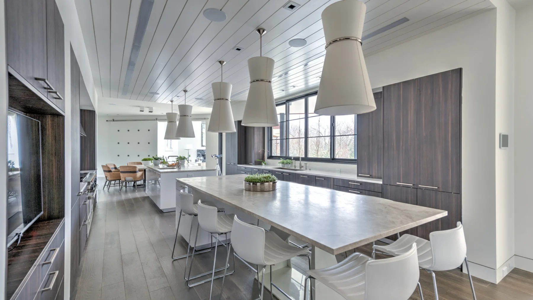 A modern kitchen and dining area with a long island and pendant lights.