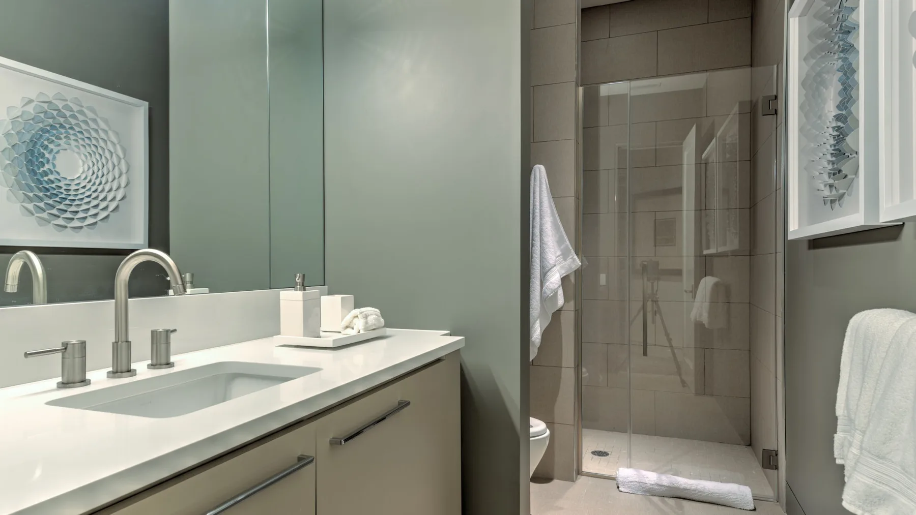 A bathroom vanity and sink sit beside a glass-enclosed shower.