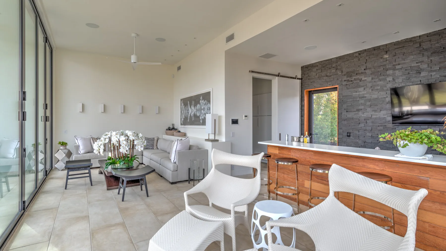 A bright open-plan living room with a seating area beside a long wooden counter.