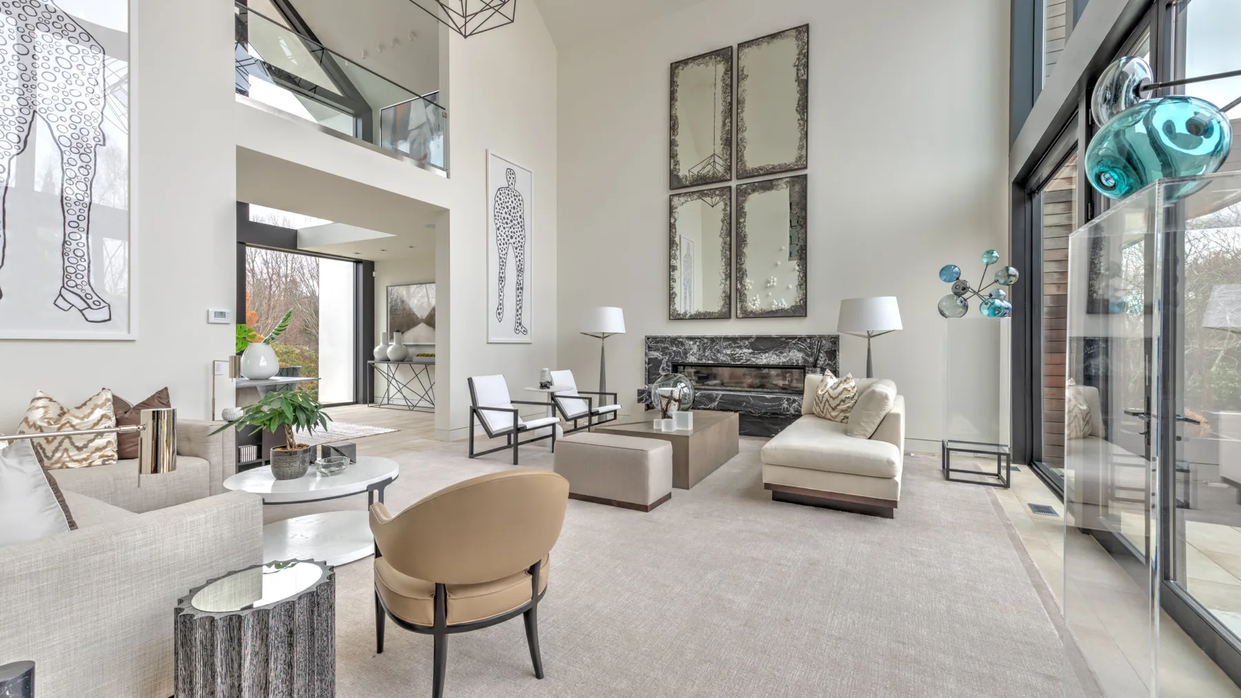 A spacious living room with seating arranged around a fireplace and large windows.
