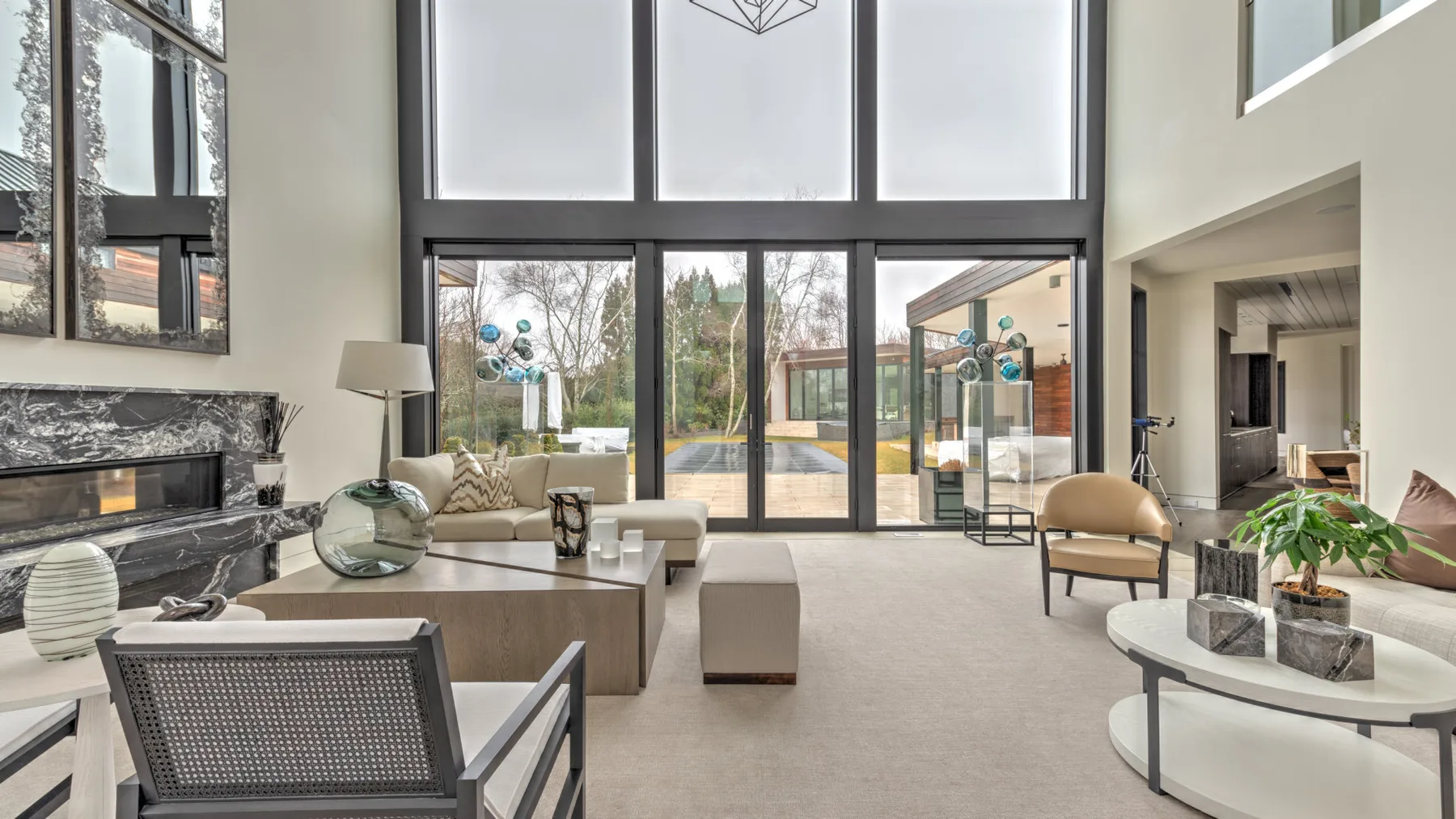 A bright living room with tall windows, seating, and a view of the garden.