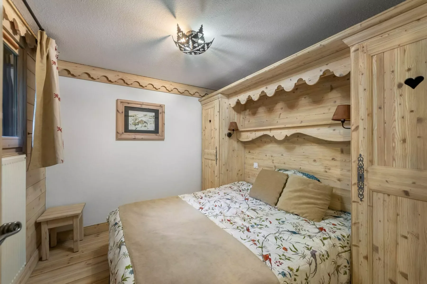 A bedroom with a floral bedspread and light wood paneling.