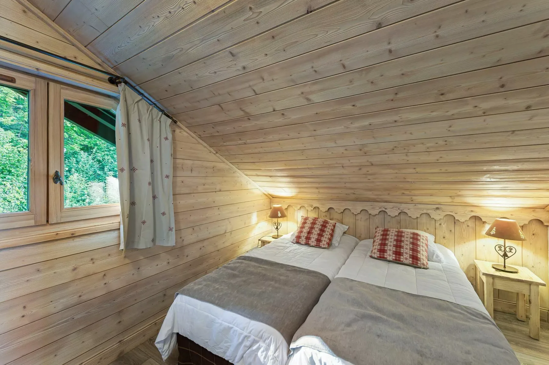 A wood-paneled bedroom with two beds beneath a sloped ceiling.
