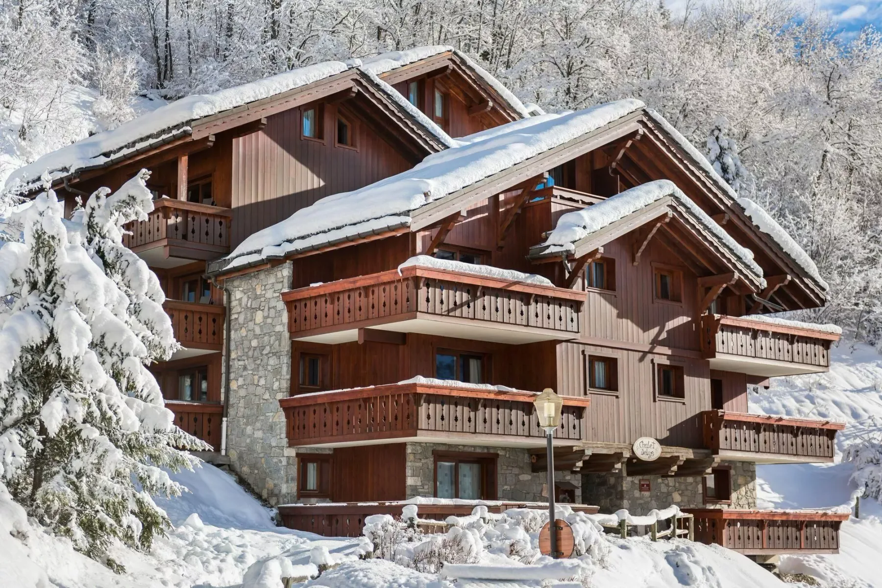 A large wooden chalet stands among snow-covered trees.