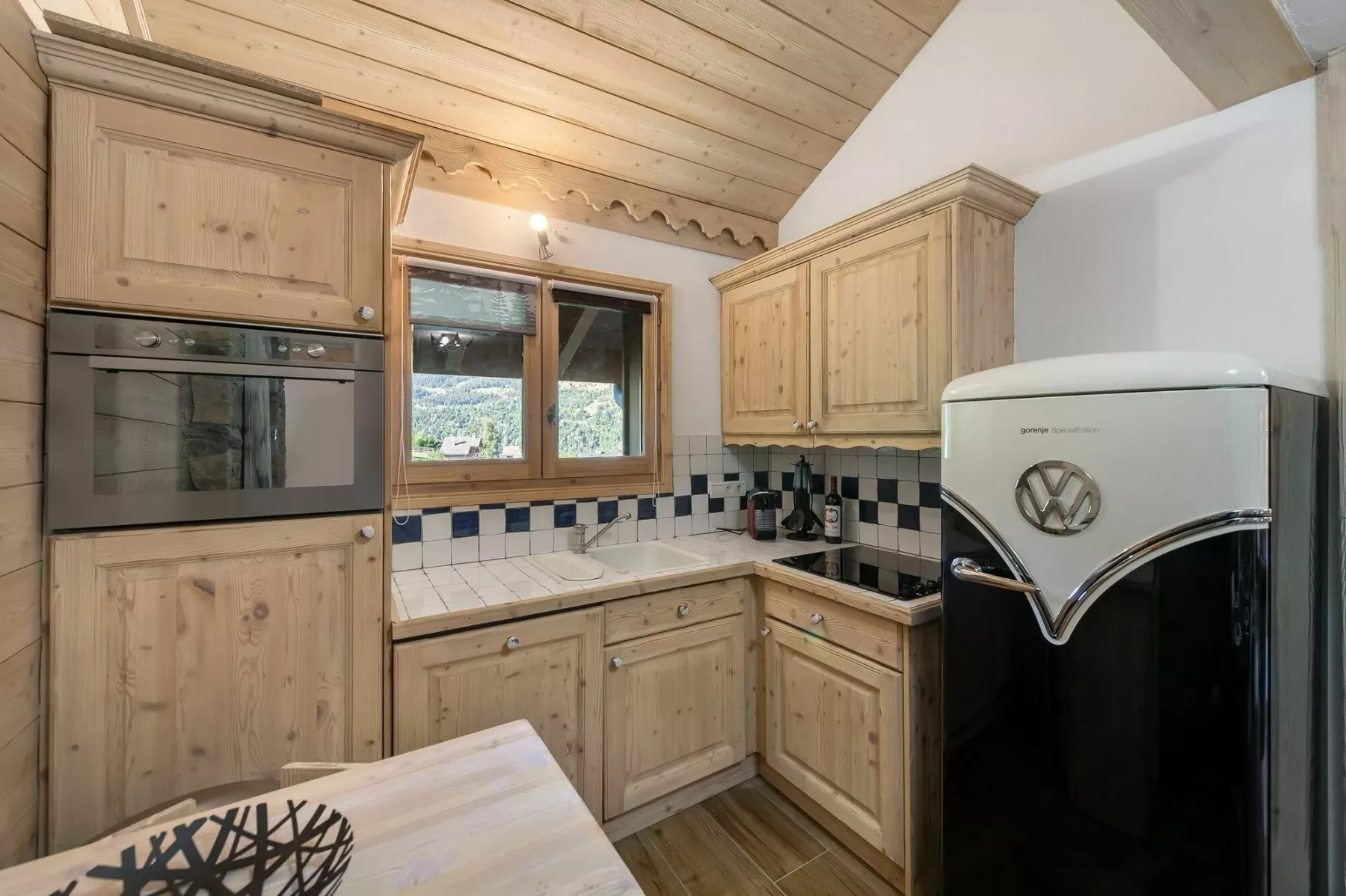 A wood-paneled kitchen with a tiled backsplash and a retro-style refrigerator.
