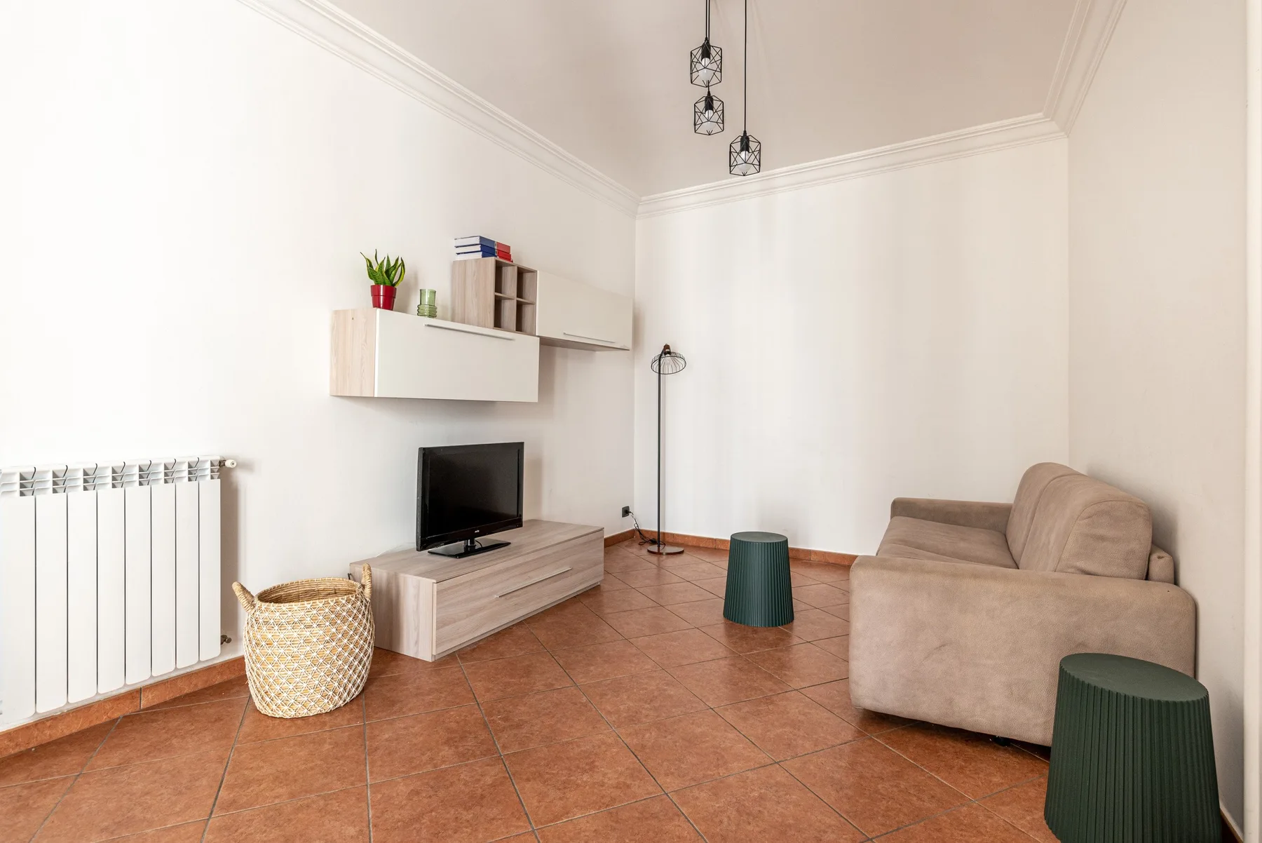 A bright living room with seating, a television, and a wall-mounted shelf.