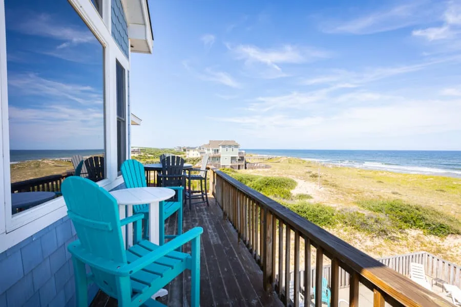 A seaside deck with turquoise seating overlooks the beach and ocean.