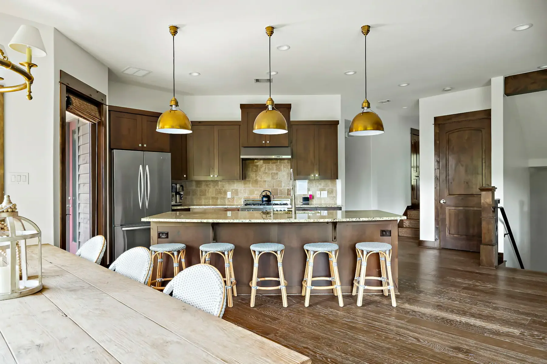A kitchen with dark cabinets, a central island, and pendant lights overhead.