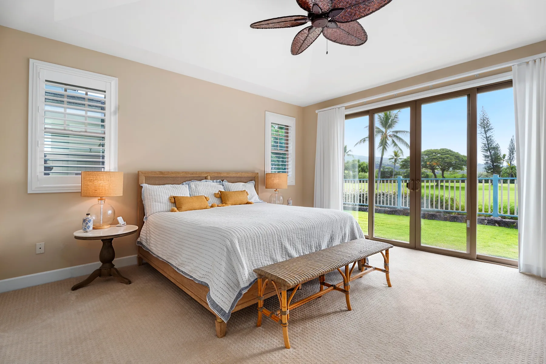 Un dormitorio luminoso con una cama arreglada y grandes puertas de vidrio con vistas a un jardín.