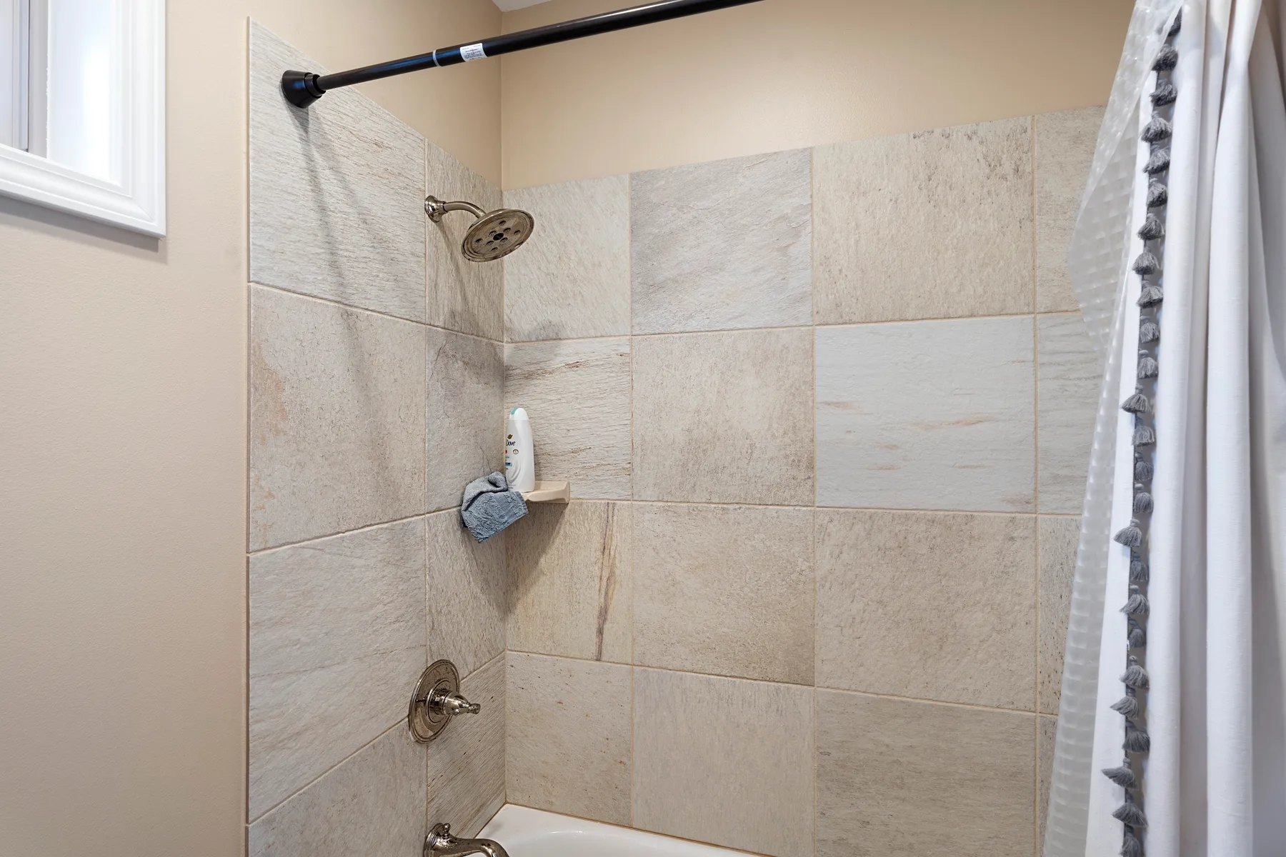 Una ducha de baño con azulejos, cabezal de ducha y cortina.