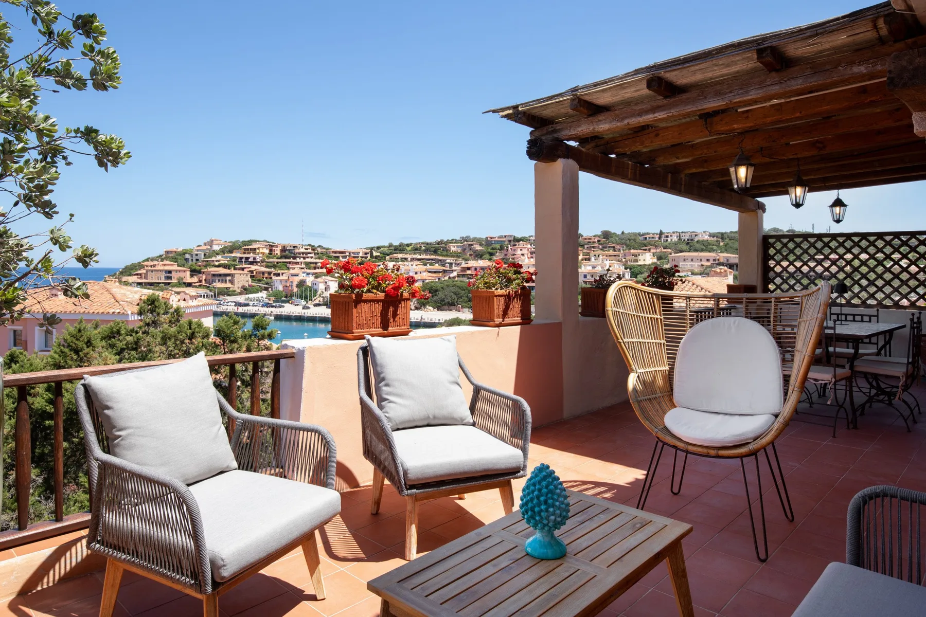 Una terraza con asientos al aire libre ofrece vistas de un pueblo costero y el agua.