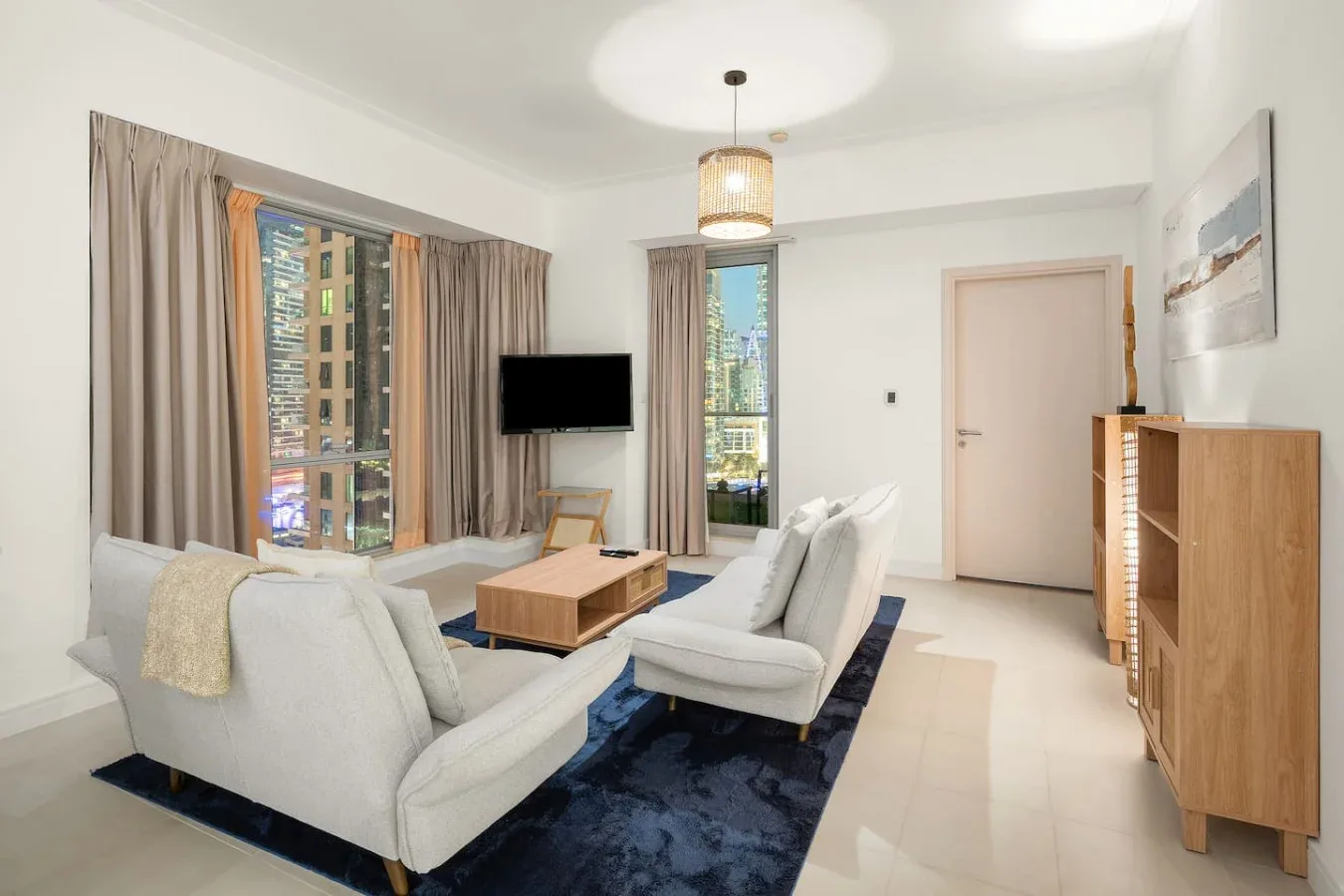 A bright living room with seating around a coffee table and large windows.