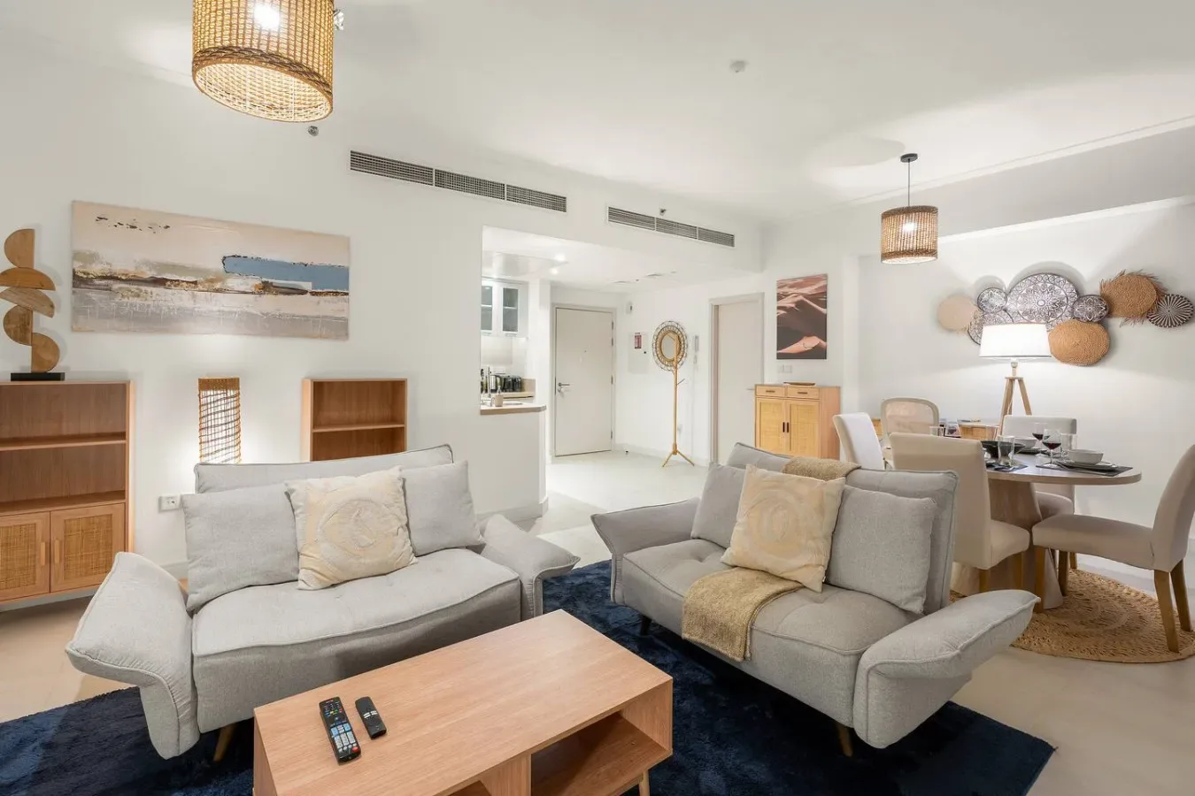 A bright open-plan living and dining area with gray seating and a wooden coffee table.