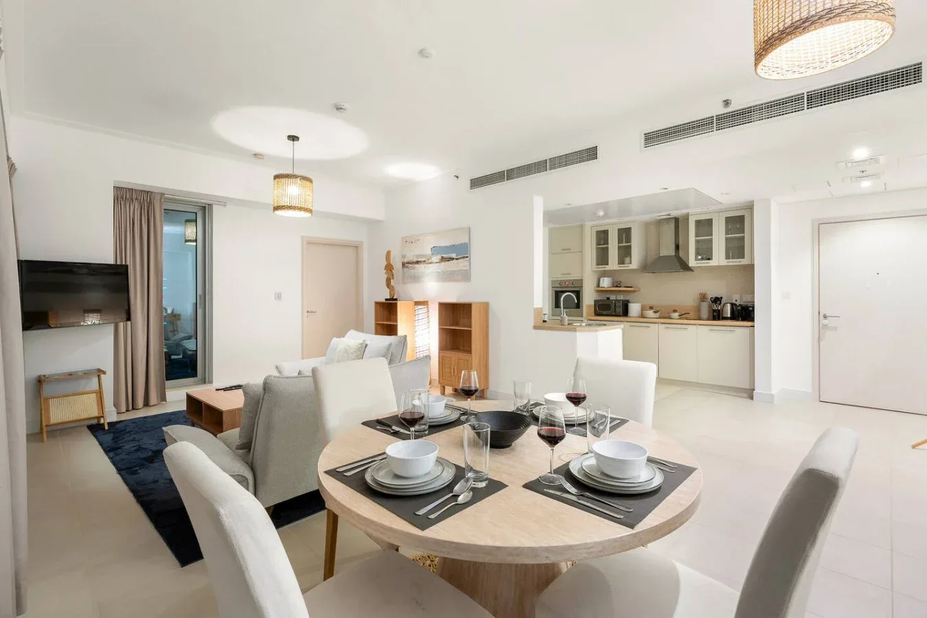 A dining area with a round table and an open kitchen behind it.