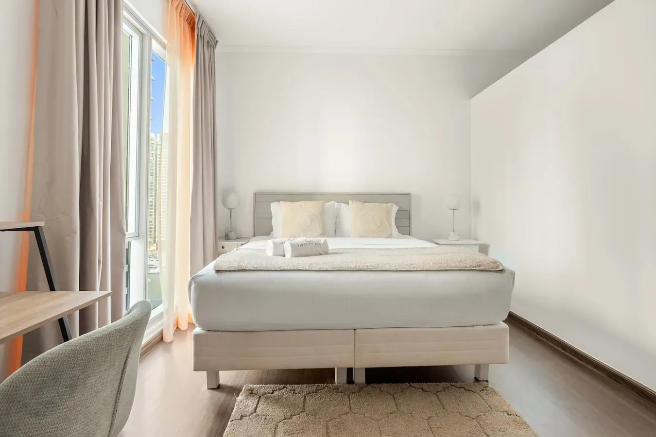A bright bedroom with a bed beside a tall window.