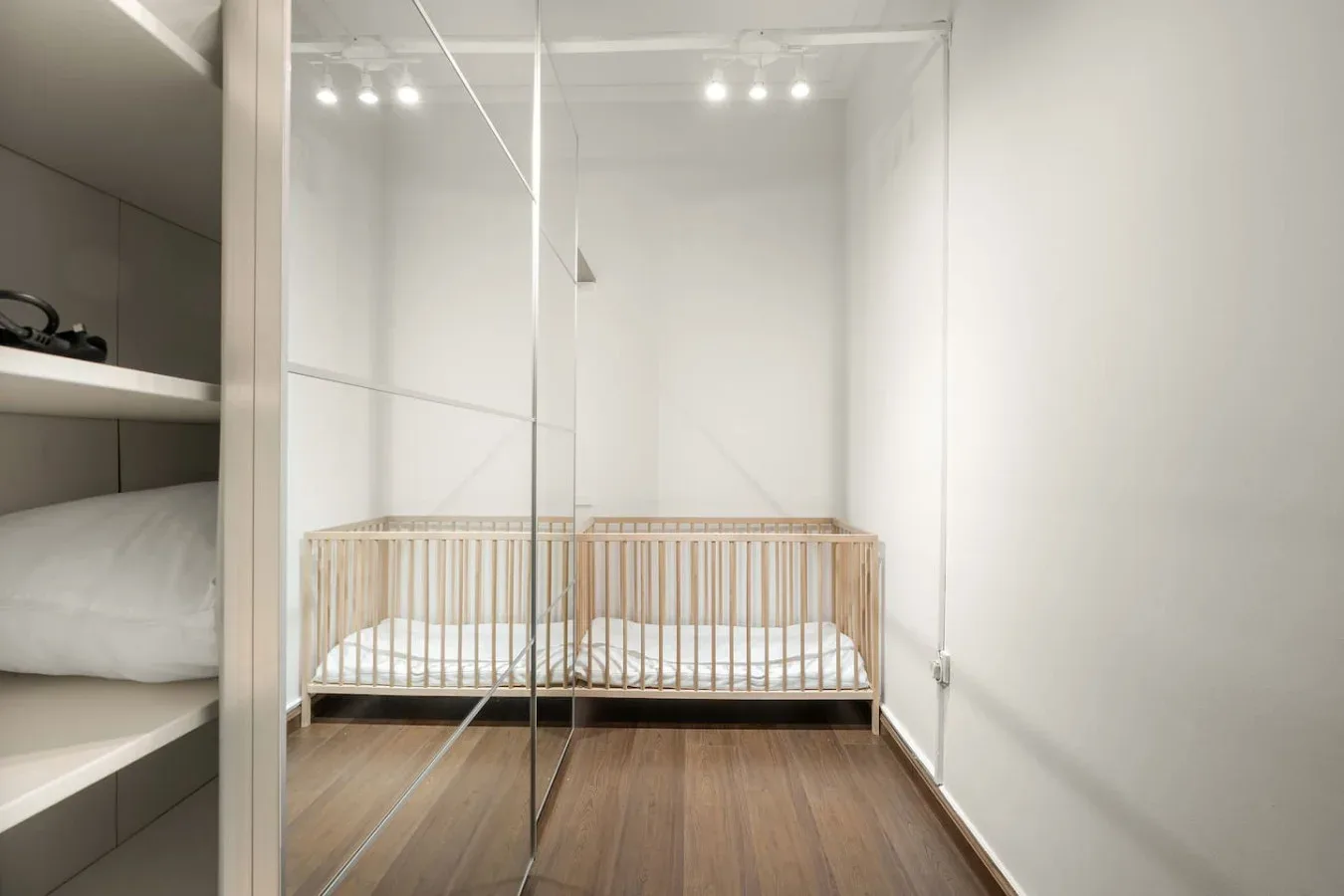 A nursery with a wooden crib and mirrored closet doors.